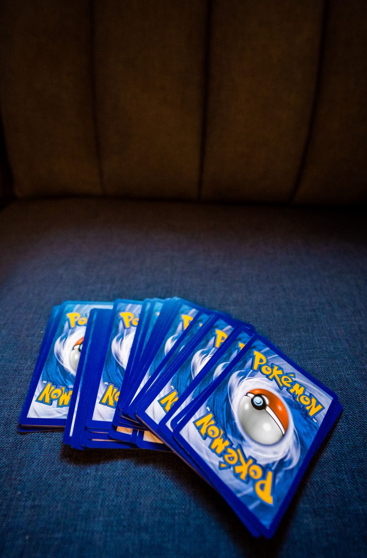 Ein Stapel Pokémon-Sammelkarten liegt aufgefächert auf einem Sofa
